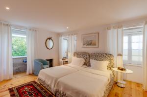 1 dormitorio con cama blanca y silla de estampado de leopardo en Casa das Laranjas, en Oporto