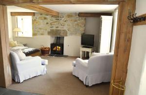 uma sala de estar com mobiliário branco e uma lareira em Bonython Farmhouse em Cury