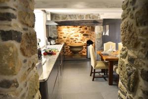uma cozinha com uma mesa e uma parede de pedra em Bonython Farmhouse em Cury