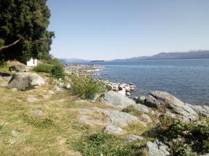 a group of rocks on the side of a body of water at Michay, bungalow 4pax, a 50 mts del lago. in San Carlos de Bariloche