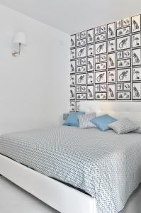 Dormitorio blanco con cama con almohadas azules en La Casetta di Posillipo, en Nápoles