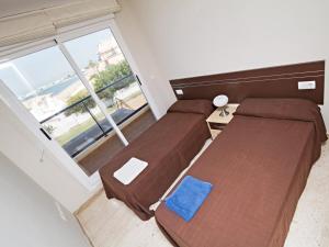 two beds in a room with a large window at Apartamentos Almadraba VyB in Denia