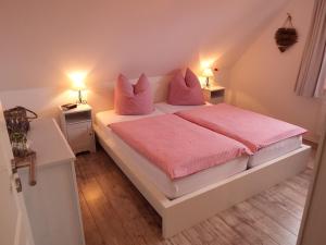 Schlafzimmer mit einem Bett mit rosa Bettwäsche und Kissen in der Unterkunft Kranichnest in Hohwacht