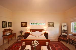 1 dormitorio con cama, mesa y piano en Guinea Fowl Lodge, en Knysna