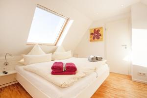 a white bedroom with two red towels on a bed at Residenz zum Südstrand/Levke in Borkum