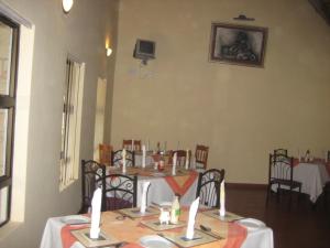 a dining room with a table with white tables and chairs at Black Swan Guesthouse in Maseru
