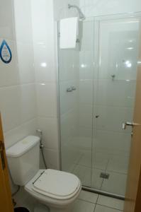 uma casa de banho com um WC e uma cabina de duche em vidro. em Ímpar Suítes Cidade Nova em Belo Horizonte