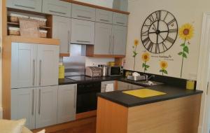 a kitchen with white cabinets and a clock on the wall at Madge House Ashbourne in Ashbourne