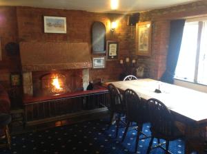 a fireplace in a dining room with a table and chairs at The Jolly Huntsman in Chippenham