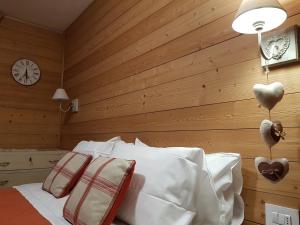 a bedroom with wooden walls and a bed with two pillows at Hotel Pedretti in Branzi