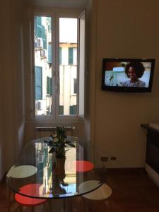 a room with a glass table and a tv on the wall at Varese Guest House in Rome