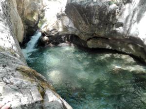 a body of water with rocks and a waterfall at Camping L'Espelt in La Pobla de Lillet