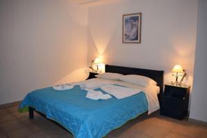 a bedroom with a bed with a blue blanket and two lamps at Votsalo Apartments in Patitiri