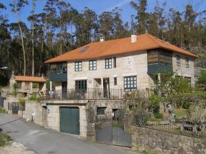 une maison ancienne avec un toit orange dans une rue dans l'établissement Casa de Labranza A Rega, à Combarro