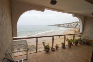 einen Balkon mit Blick auf einen Strand mit Topfpflanzen in der Unterkunft Appartement Taghazout in Taghazout