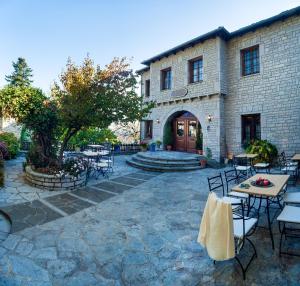 a patio with tables and chairs in front of a building at En Chora Vezitsa in Vitsa