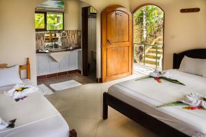 two beds in a room with a door to a kitchen at Hotel Rancho Corcovado in Drake