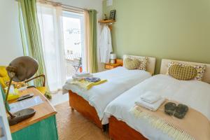 a bedroom with two beds and a desk and a window at Ghand in-Nanna B&B in Mellieħa
