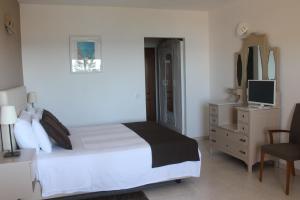 a bedroom with a bed and a desk and a television at Vivenda Solmar in Lagos