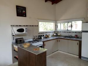 y cocina con fogones y microondas. en Los Pinos - Costa del Este - Casa 6 personas en Costa del Este