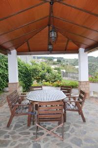 a wooden table and chairs under a wooden roof at Casa Huerta San Francisco in Casarabonela