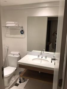 a bathroom with a sink and a toilet and a mirror at Rio Stay Rio Centro in Rio de Janeiro