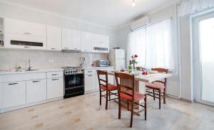 kuchnia z białymi szafkami i stołem z krzesłami w obiekcie Apartments Andela w mieście Brseč +18 zdjęć