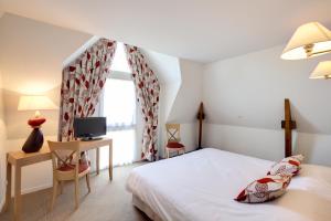 a bedroom with a bed and a desk and a tv at Les Ormes Domaine et Resort in Epiniac