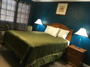 a bedroom with a bed with a green bedspread and two lamps at Aristocrat Motel in Baldwin Park