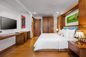 a bedroom with a large bed and a flat screen tv at Paris Deli Danang Beach Hotel in Danang