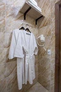 a white robe is hanging on a wall in a bathroom at MAXX inn in Astana