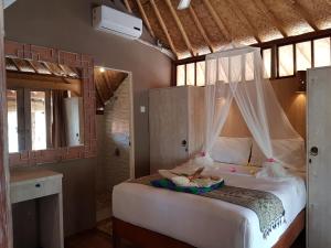 una camera da letto con un letto a baldacchino di Puri Air Beach Resort & Spa a Gili Air Altre 70 foto