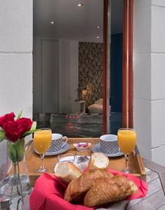 - une table avec du pain et deux verres de jus d'orange dans l'établissement Hotel La Font Vineuse & Spa, à Saint-Pierre-dʼArgençon