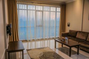 a living room with a couch and a table and a large window at Barka Hotel Apartment in Samhān