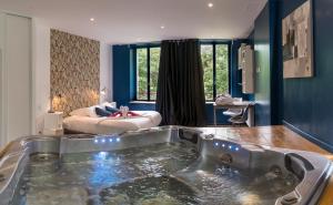 a bathroom with a tub in the middle of a room at Hotel La Font Vineuse & Spa in Saint-Pierre-dʼArgençon