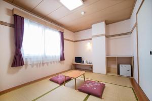 a room with a table and two pink pillows at Hotel All In Stay Hakodate in Hakodate