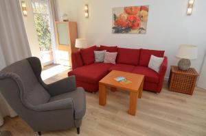 a living room with a red couch and a chair at Villa am Park - Apt. 02 Düne in Ostseebad Sellin