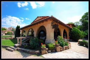 un petit bâtiment avec des plantes et des fleurs dans une cour dans l'établissement Raco del Tosca, à Beceite