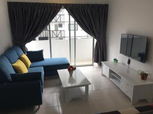 a living room with a blue couch and a tv at Cameron Prima Apartment @ Cameron Jaya in Cameron Highlands
