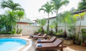 a resort pool with lounge chairs and palm trees at Palmview Resort in Patong Beach