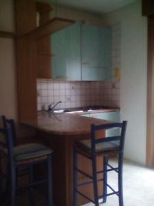 eine Küche mit einer Theke mit 2 Stühlen und einem Waschbecken in der Unterkunft Appartamento Perco Riva Slataper in Grado