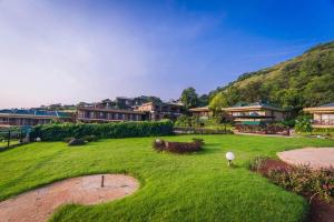 a large grassy yard with buildings in the background at Upper Deck Resort in Lonavala