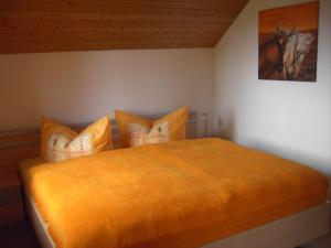 a bedroom with a large orange bed with pillows at Friesenhof Blank in Sulzberg