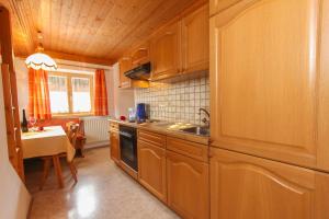 a kitchen with wooden cabinets and a sink and a table at Mosshamhof in Saalfelden am Steinernen Meer