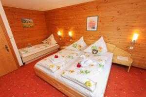 two beds in a room with wooden walls at Mosshamhof in Saalfelden am Steinernen Meer