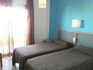 a bedroom with two beds and a blue wall at Apartamentos Ágata V.v. in La Manga del Mar Menor