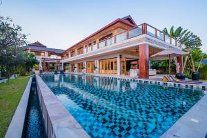 a large swimming pool in front of a house at Baan Jintana in Cha Am