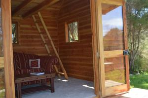 a door to a log cabin with a bench and a table at First Light Rangihaeata Retreat in Takaka
