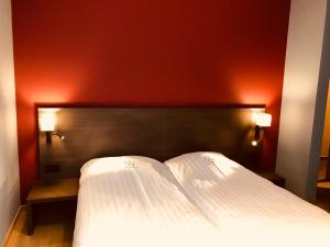 a bedroom with a white bed with a red wall at Hotel De Franse Kroon in Diest