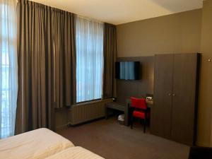 ディーストにあるHotel De Franse Kroonのベッド、デスク、窓が備わるホテルルームです。